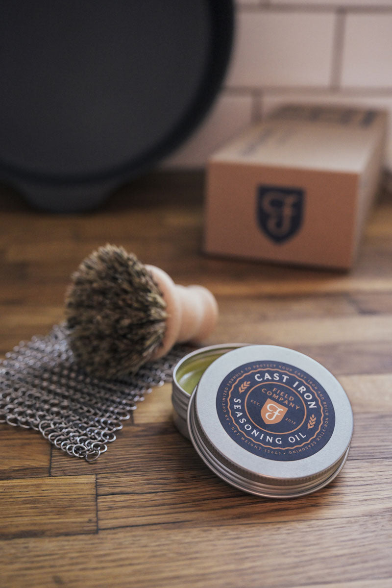 Cast iron brush, chain mail and seasoning on a kitchen counter